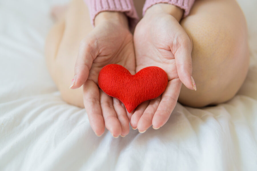 A small fabric heart resting in two open hands.